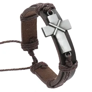 Detail of vintage braided leather bracelet featuring an antique silver cross charm centerpiece