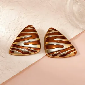 Macro shot of triangular tiger print enamel earrings with golden vintage stripes