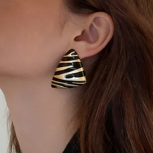 Close-up of zebra pattern triangle earrings with black enamel on a female model
