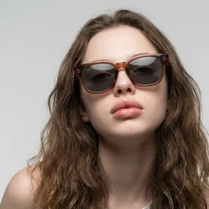 Chic amber square sunglasses with dark grey lenses worn by a model in a close-up shot