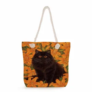 Detail of canvas tote bag featuring black cat and orange lily print with cotton rope handle
