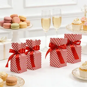 Red and white striped gift boxes with satin ribbons arranged on a celebratory party table