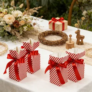 Close-up of red and white striped gift boxes with elegant satin bow on a wooden table