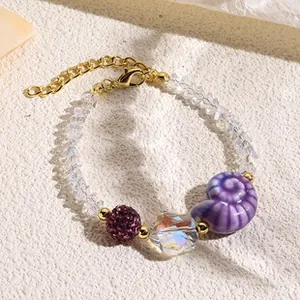 Detail of beaded bracelet featuring a purple sea snail charm and multifaceted crystal beads