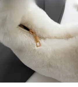 Close-up of a smooth gold metal zipper on a soft white plush handbag detail