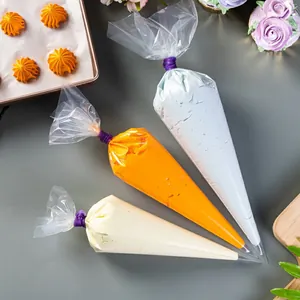 Three disposable piping bags with blue and orange frosting and purple ties on a baking mat