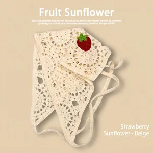 Détail du bandana au crochet crème avec appliques de fraises rouges et motifs ajourés