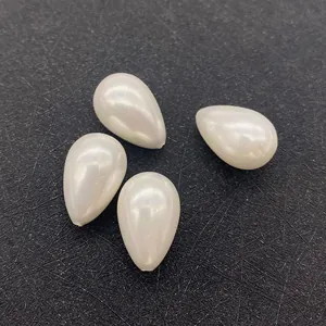 Détail de quatre perles d'imitation en forme de goutte avec un éclat blanc crème irisé