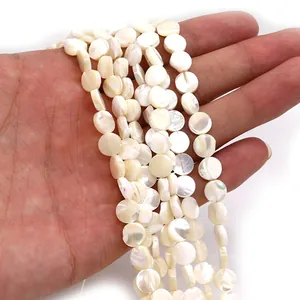 Macro shot of natural white mother of pearl shell disc beads held in hand for jewelry DIY
