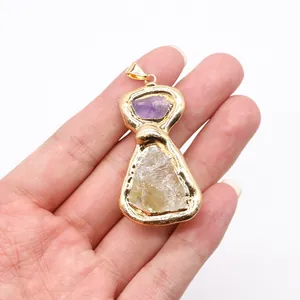 Detailed view of hand-held gold plated raw amethyst and citrine crystal stone pendant