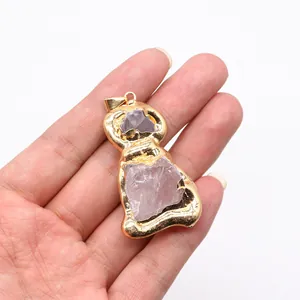 Close-up of natural purple raw stone pendant in a gold-plated figure-8 frame on a hand