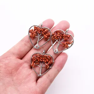 Detailed close-up of handmade heart-shaped Tree of Life pendants with red stone chips