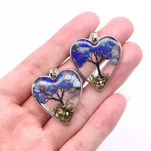 Vista macro de dos colgantes de corazón hechos a mano con el diseño del Árbol de la Vida en plata