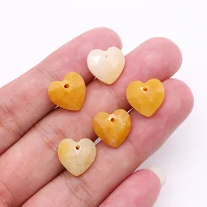 Detalle de cinco colgantes de corazón facetado en piedra ojo de tigre amarilla en la mano