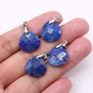 Macro detail of four faceted lapis lazuli teardrop pendants held in hand with silver bails