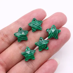 Macro view of five pointed star shaped malachite pendants held to show mini size