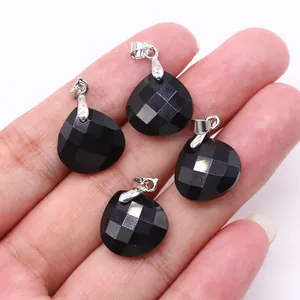 Close-up of four faceted black stone teardrop pendants with silver clasps held in hand