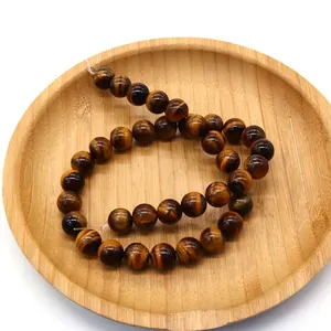 Polished natural tiger eye round beads for jewelry making on a wooden display tray
