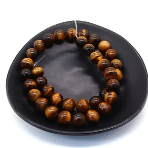 Polished natural tiger eye stone beads with golden chatoyancy on a black ceramic plate
