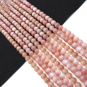 Polished natural orange sunstone beads for DIY jewelry making displayed on a dual-tone background