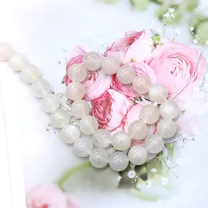 Polished white moonstone beads string for DIY necklaces and bracelets on floral background