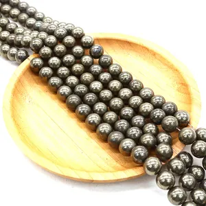 Natürliche Chalkopyrit-Rundperlen mit Metallglanz auf hellem Holztablett für DIY-Schmuck