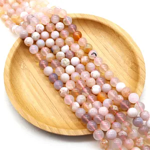 Polished natural sakura agate round beads for DIY jewelry making on wooden tray