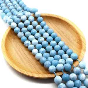 Polierte Larimar-Rundperlen mit blau-weißer Marmorstruktur auf einem Holztablett