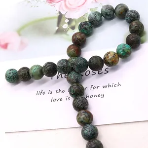 Natural African turquoise round beads for DIY jewelry making on white card with roses