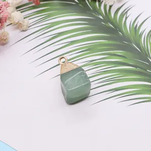 Detailopname van groene natuurstenen hanger met vergulde kap en bloemdecoratie