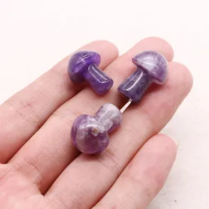 Close-up of three mini amethyst mushroom carvings held in hand showing scale and natural texture