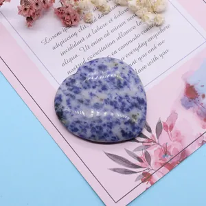 Nahaufnahme von herzförmigem Blaustrom-Naturstein mit polierter Textur auf rosa Karte