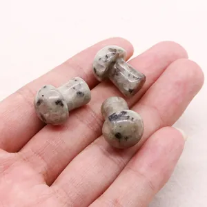 Macro shot showing small mushroom-shaped natural stones with black spotted texture on hand