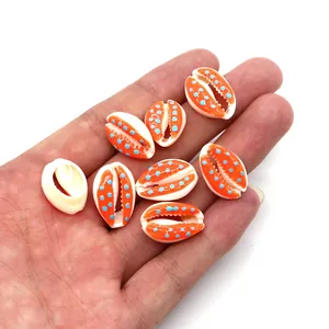 Detail of orange cowrie shell charms with blue dots for DIY jewelry making