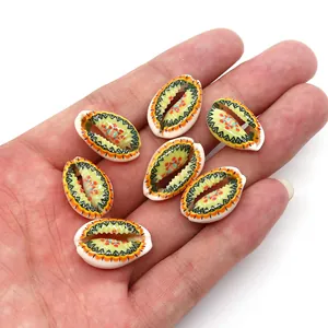 Hand-painted natural cowrie shell beads with colorful wave patterns shown in palm for scale