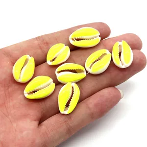 Macro view of eight yellow and white candy-colored shell beads held by a hand