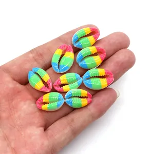 Close-up of rainbow striped cowrie shell beads for DIY jewelry held in hand for scale