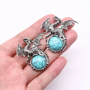 Close-up of vintage viking dragon pendants holding turquoise stones in silver finish