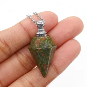 Dettaglio macro del ciondolo porta profumo in cristallo unakite tenuto tra le dita