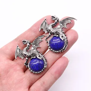 Detailed view of two vintage silver dragon pendants clutching round blue natural stones