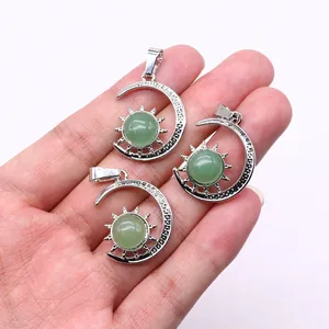 Three celestial sun and moon pendants with green gemstones held in hand for scale