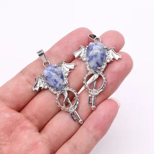 Detail of silver angel wing key pendants with blue marble stones held in hand