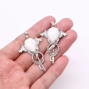Gothic silver angel wing key pendant with white turquoise stone held in hand