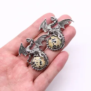 Detail showing hand holding silver Viking dragon pendants with dalmatian jasper stones