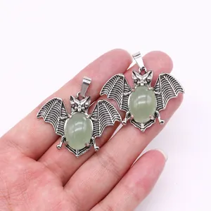 Macro view of bat-shaped vintage silver alloy pendants with green gemstone inlays
