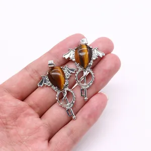 Detail of tiger eye stone pendant with angel wings and vintage key design on a palm