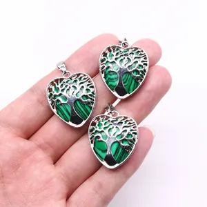 Three heart-shaped life tree pendants with green malachite texture held in hand for scale