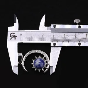 Detail shot of sun and moon pendant measured with a caliper showing 2.6cm width