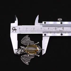 Detail van vleermuis hanger met ambersteen en afmeting met schuifmaat getoond