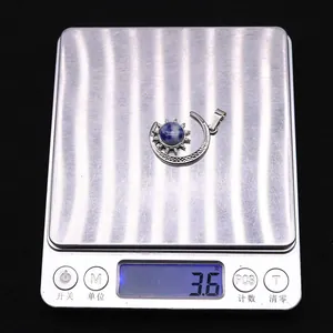 Macro detail of moon and sun pendant with blue stone on scale weighing 3.6 grams